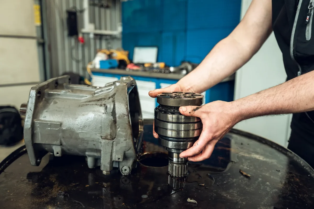 Mechanik trzyma zespół wirujący z wałkiem wielowypustowym obok obudowy hydraulicznej jednostki tłoczkowej