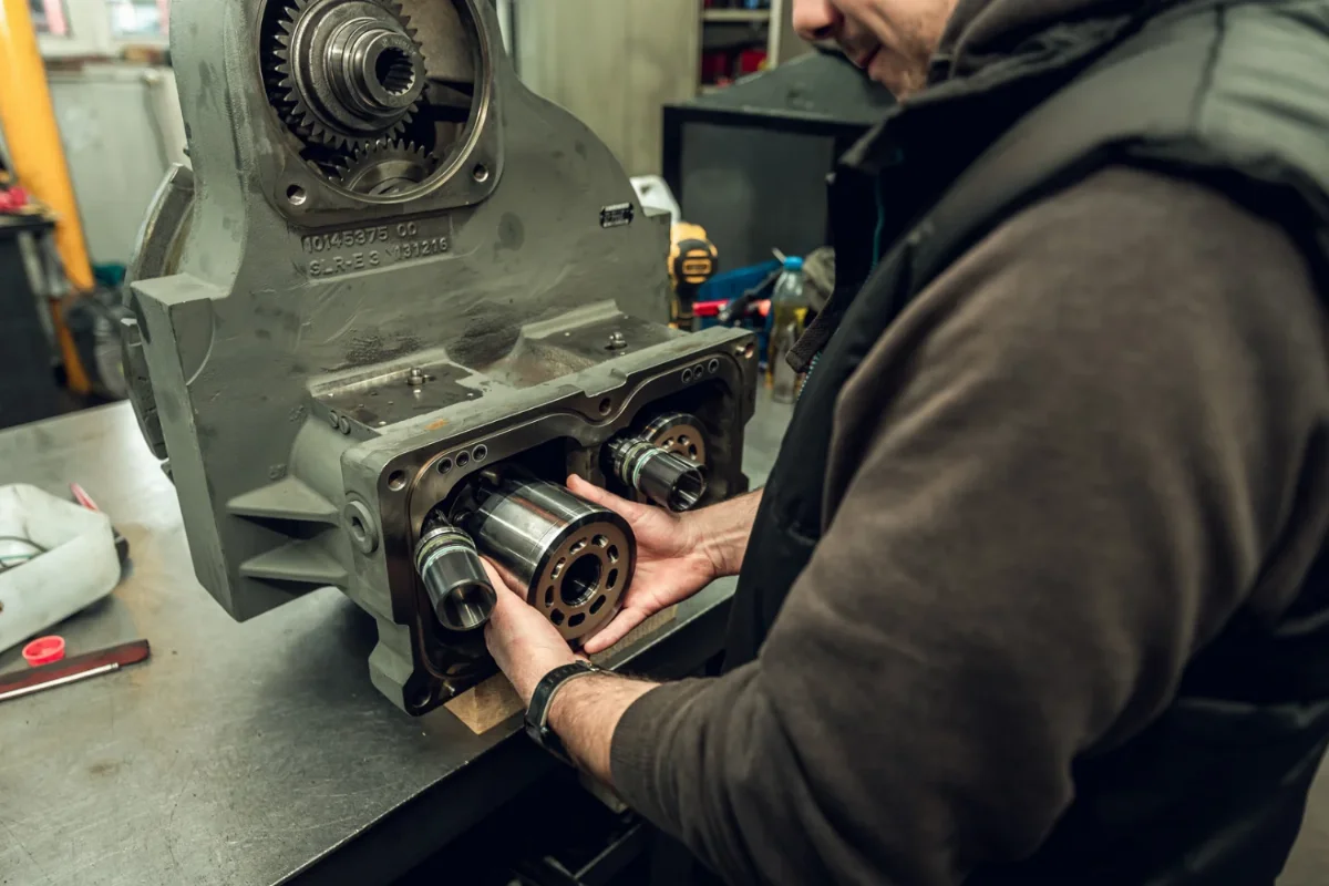 Mechanik wkłada blok cylindrowy z tłoczkami do korpusu przekładni hydraulicznej podczas montażu