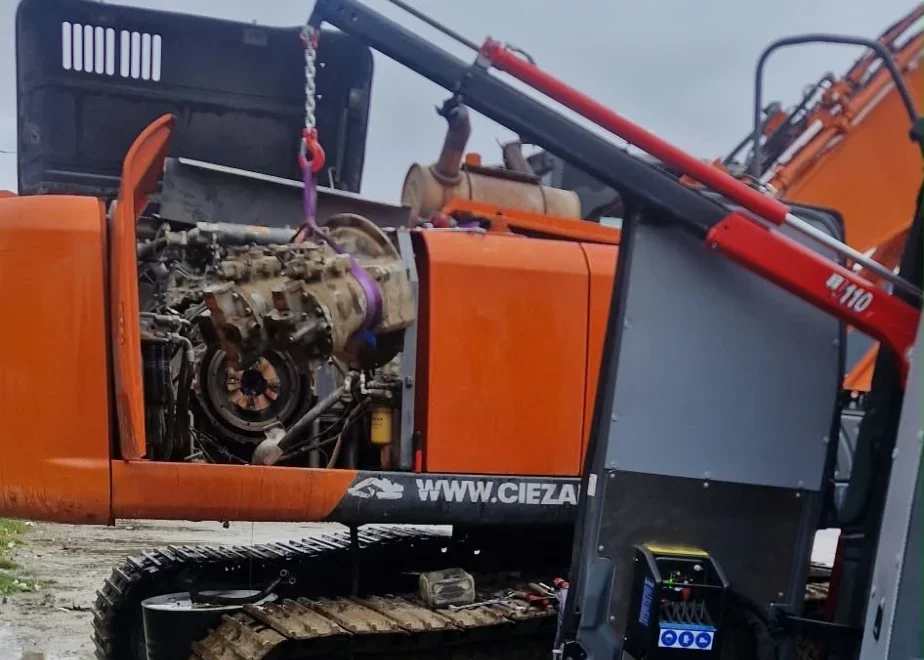 Pompa hydrauliczna Hitachi ZX350LC-3 wyjmowana z przedziału maszyny na zawiesiu żurawika z busa serwisowego